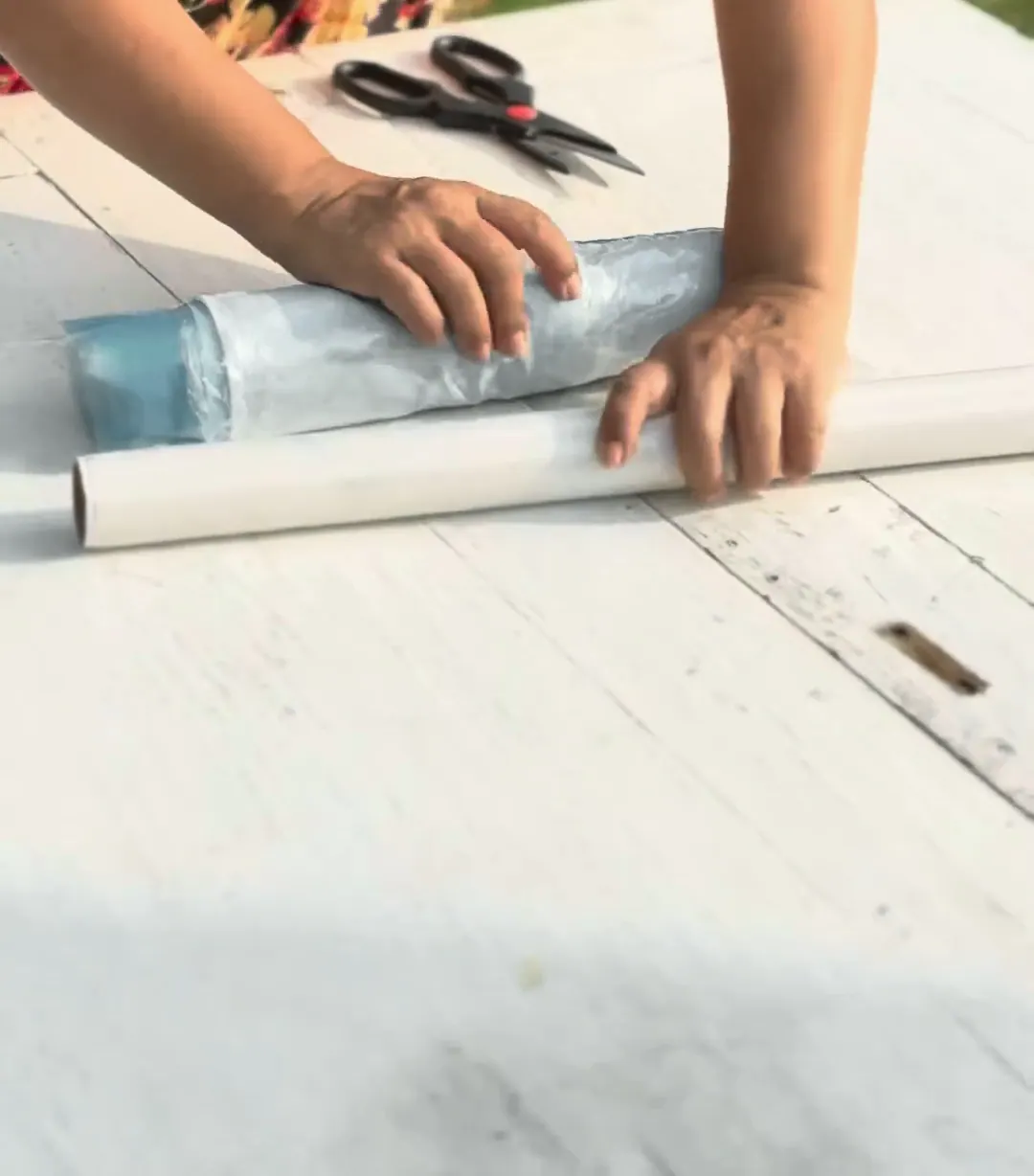 The covered cloth is rolled tightly around a pipe on a white table.