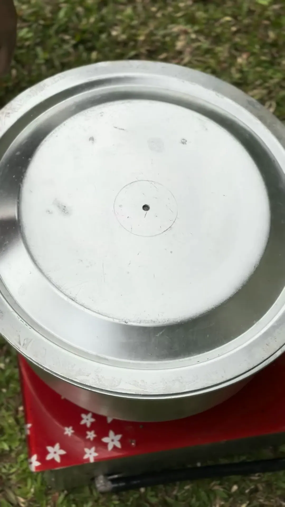 The lid is lifted from a steamer pot to show the tied bundles inside.