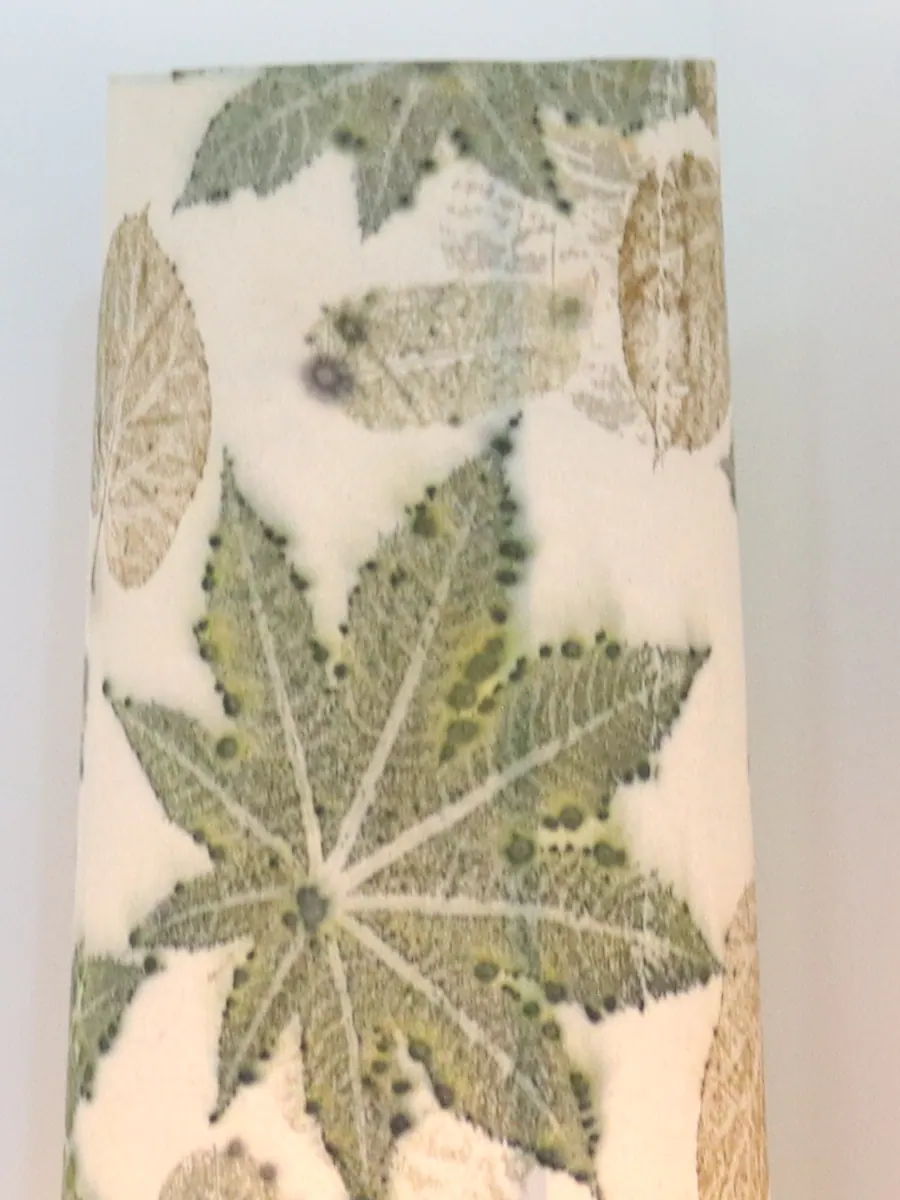 Close-up of the lamp shade: a palmate leaf print with fine pale veins on warm ivory cloth.