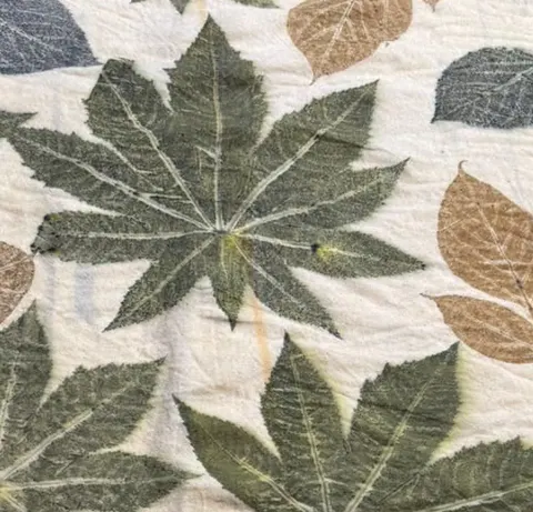 Close-up of a large palmate leaf print in sage green with pale radiating veins.